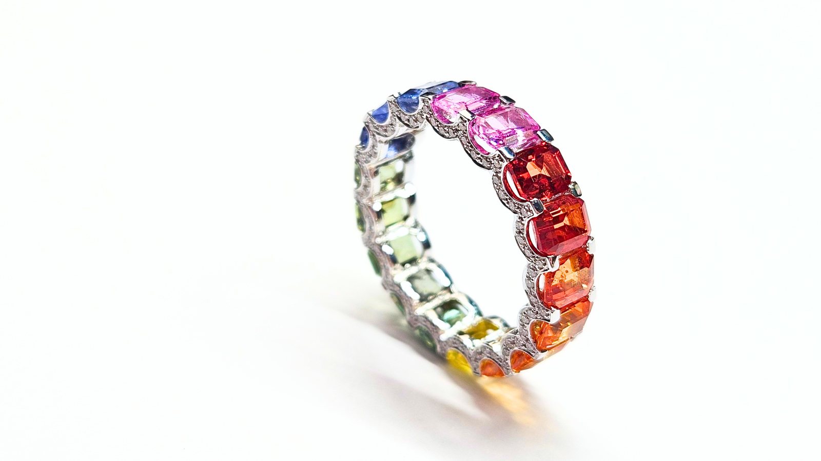 An eternity band set with fancy sapphires in blue, pink, orange, yellow and green